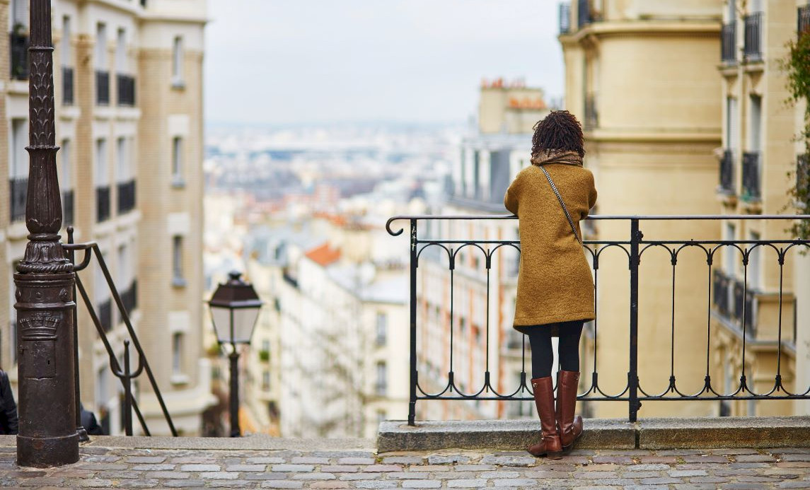 woman standing on a terrace, overlooking Paris