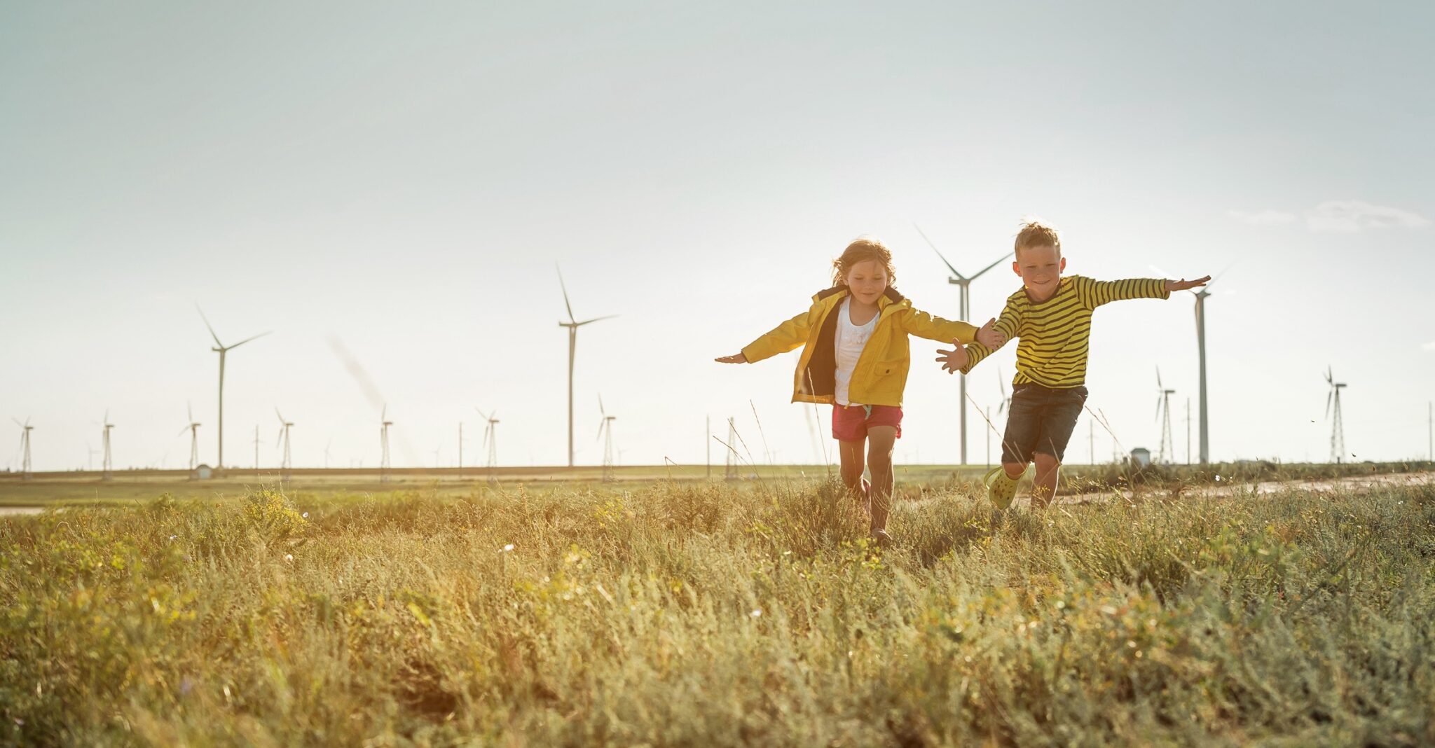 children playing in a field with wind turbines