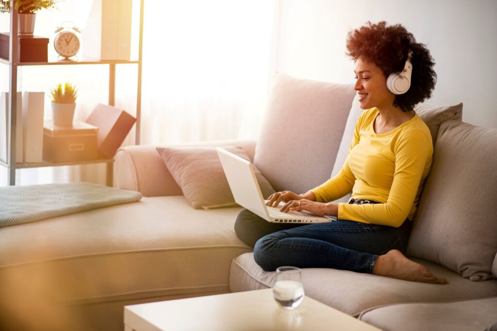 Women enjoying her home space sitting on the coach while on the computer.