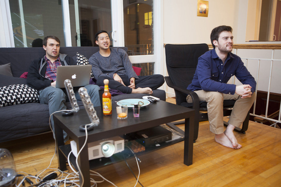 Guys hanging out in their apartment socializing and getting work done.