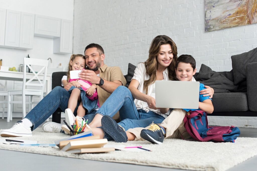 Family enjoying downtime with their two children. One and girl and the other a boy. While they enjoy leisurely use of mobile devices.