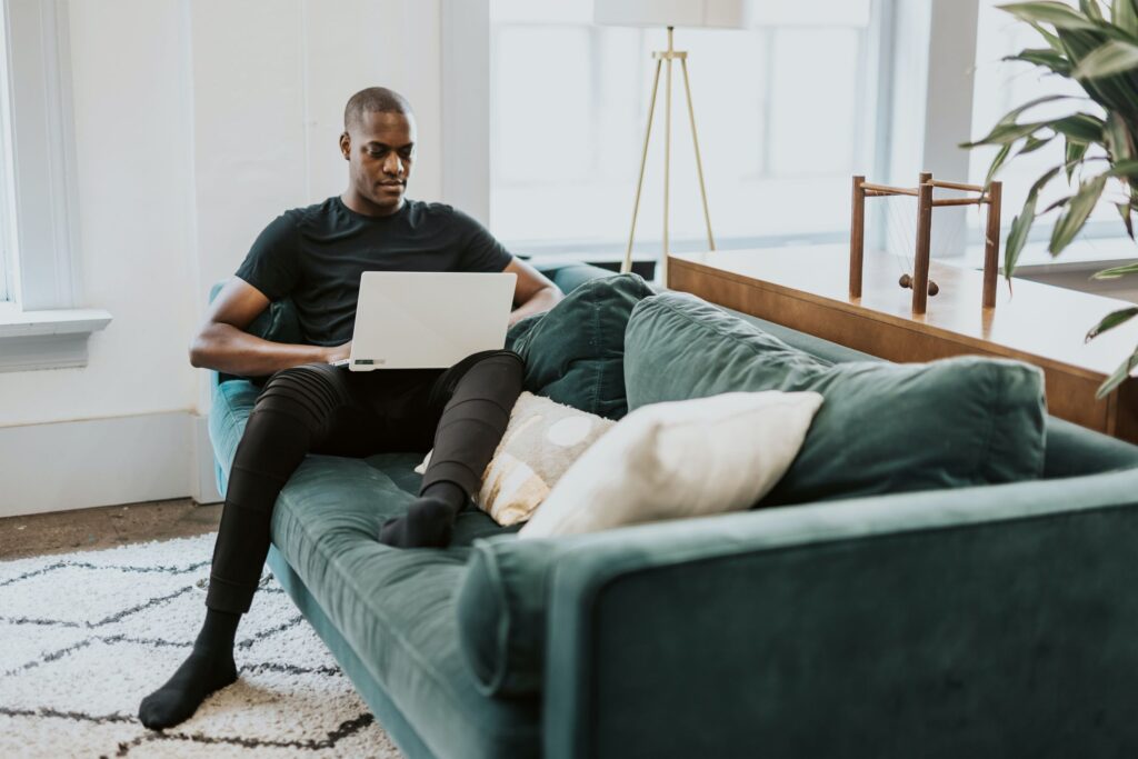 Man sitting on the coach and on the computer.