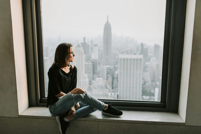 Woman sitting next to window.