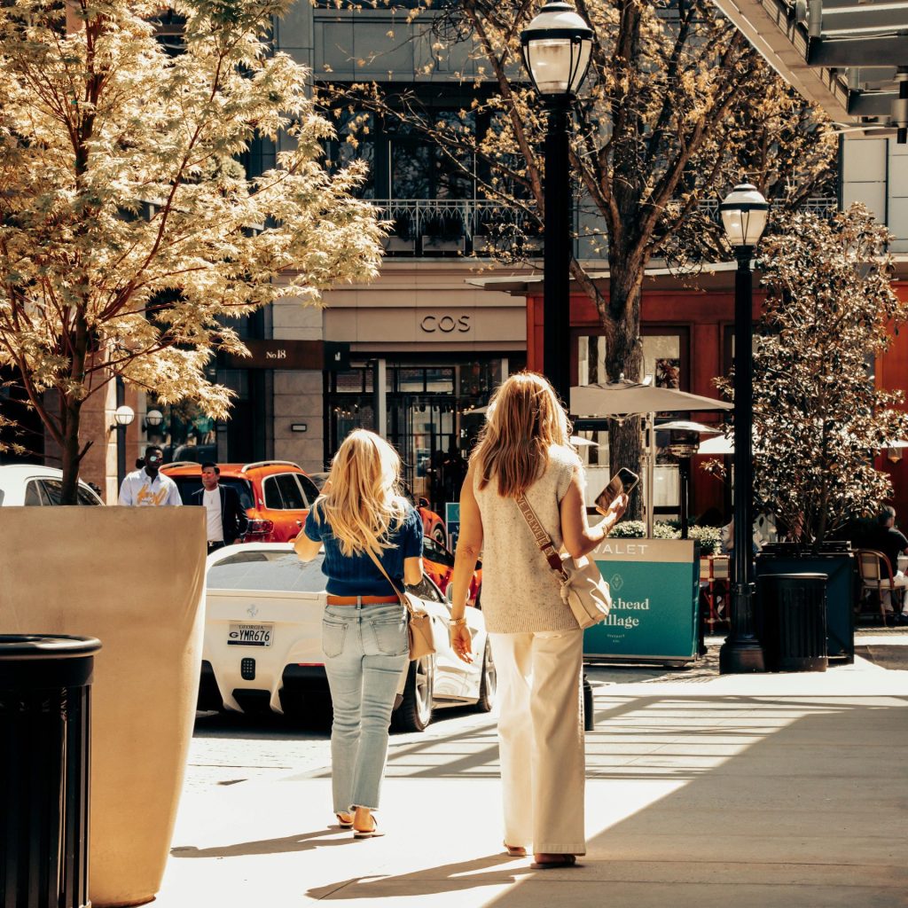 Two women walking along a sidewalk.