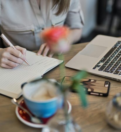 Person writing in a notebook on their desk.