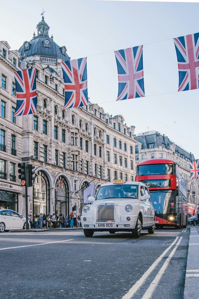 A taxi and bus driving down the streets of London.